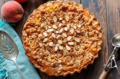 Peach Crumble Pie on a table with an ice cream scoop and pie spatula