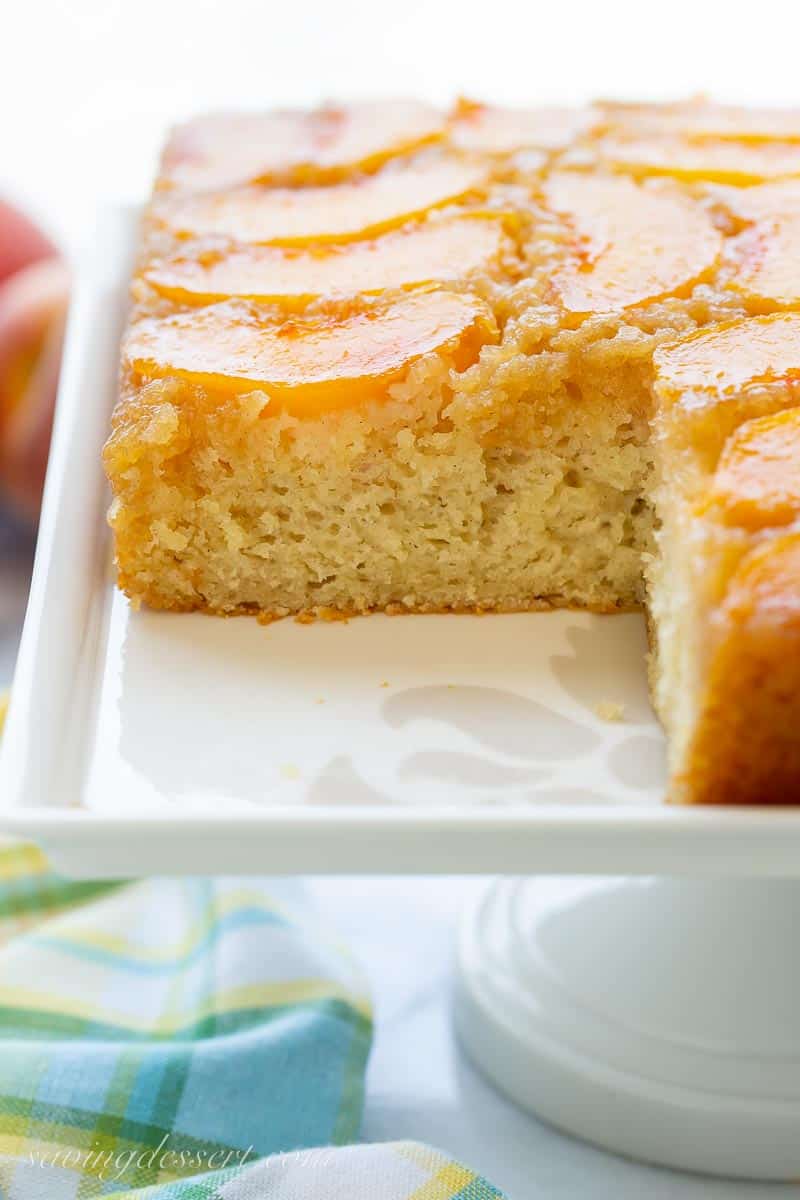 side view of a sliced peach upside down cake on a cake platter