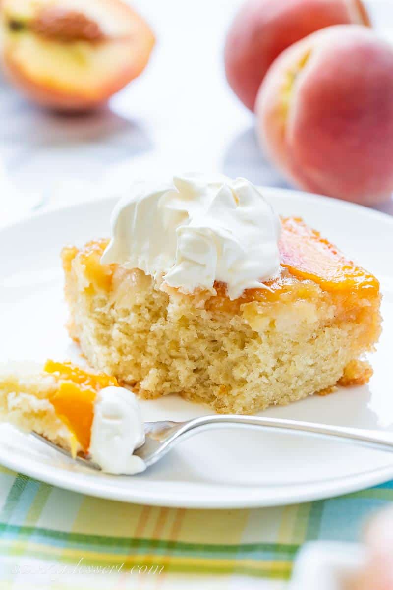 A piece of Peach upside-down cake on a plate with whipped cream