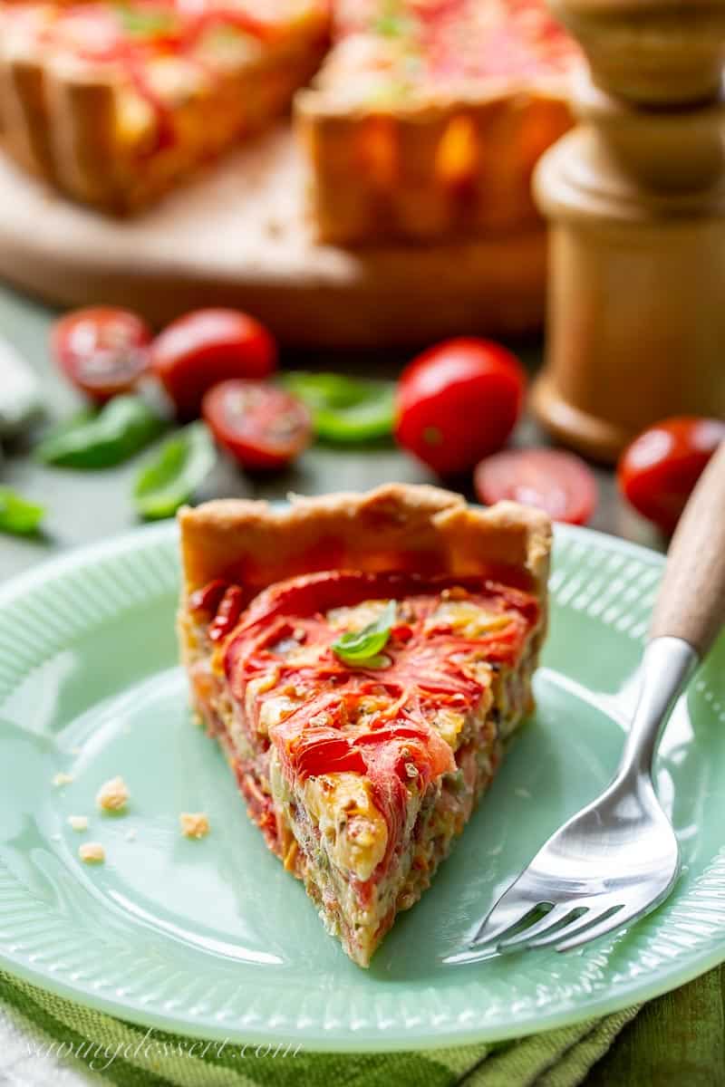 A slice of tomato pie on a plate with a fork