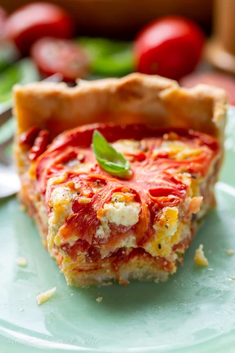 A closeup of a slice of fresh tomato pie on a green plate