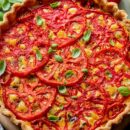 A closeup of a tomato pie topped with basil leaves