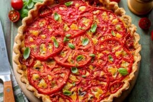 A closeup of a tomato pie topped with basil leaves