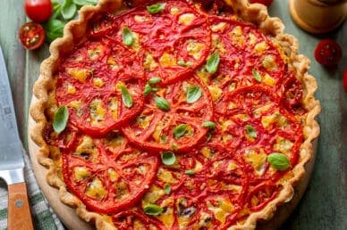 A closeup of a tomato pie topped with basil leaves