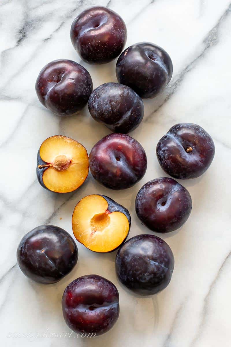 fresh black plums on a marble slab