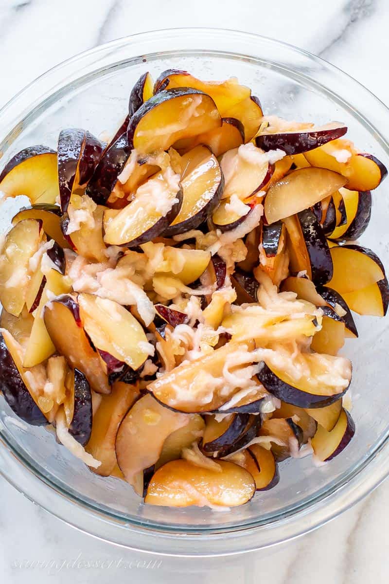 A bowl of sliced plums with shredded apple