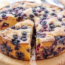 A sliced round blueberry cornbread cake on a cutting board
