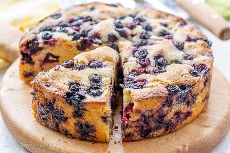 A sliced round blueberry cornbread cake on a cutting board