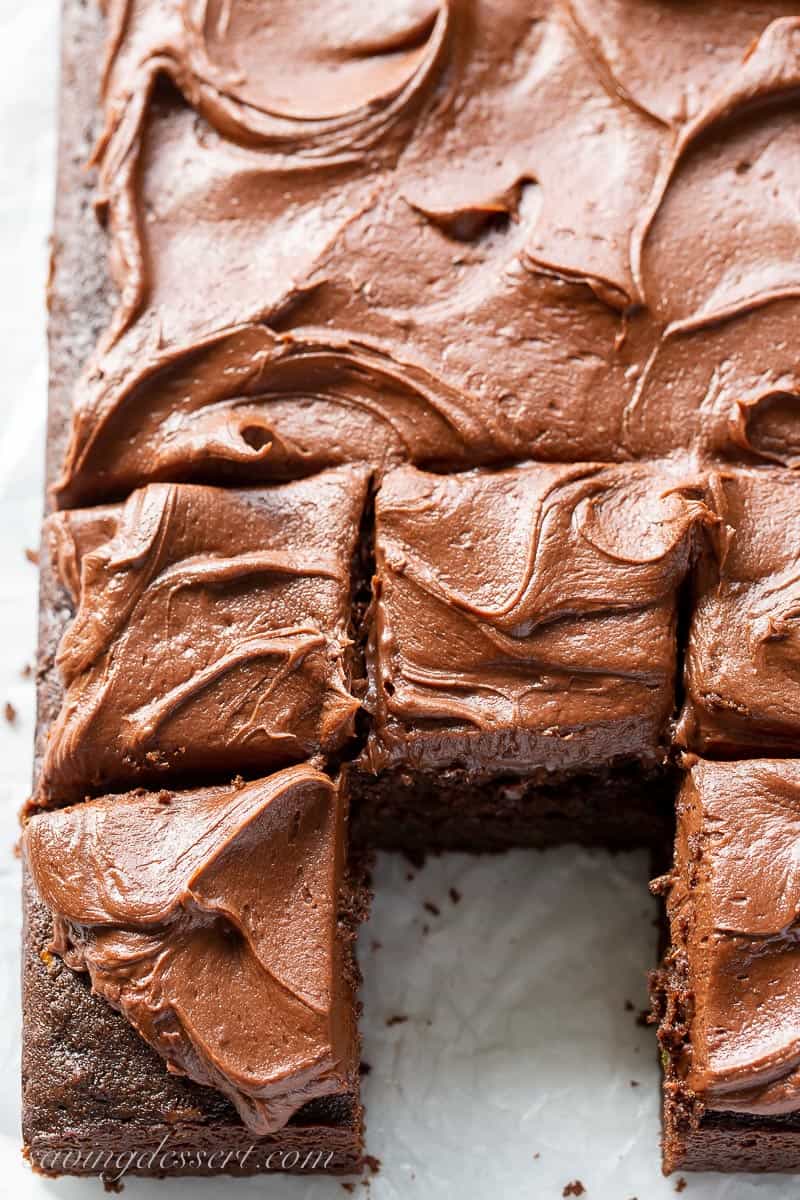 A sliced chocolate sheet cake with a square slice removed