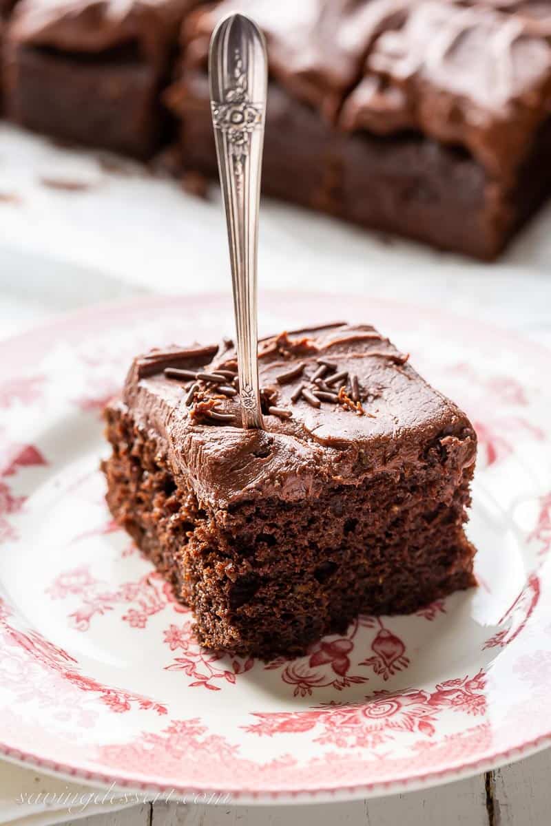 A piece of chocolate cake with chocolate frosting on a plate with a fork