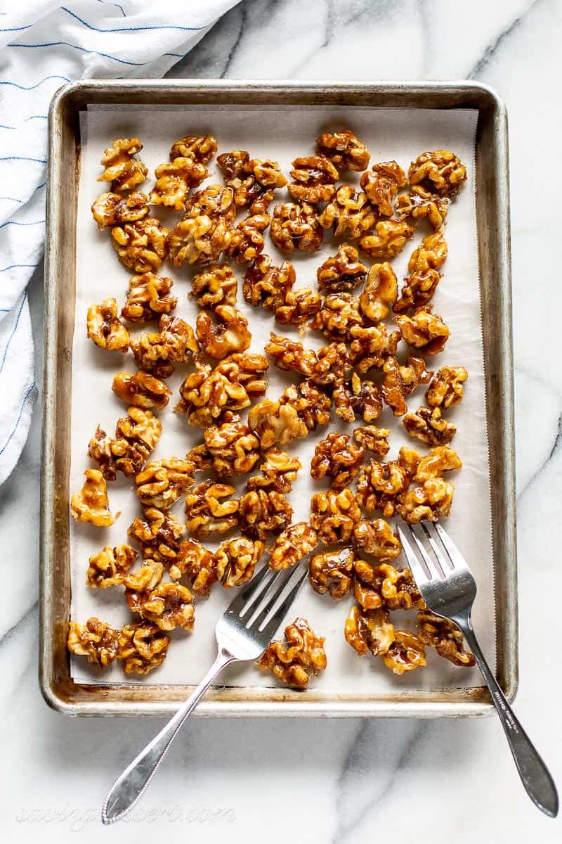 A baking tray with candied walnuts being separated with a fork