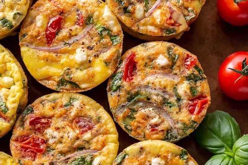 Egg muffins with tomato, feta and onion on a baking sheet