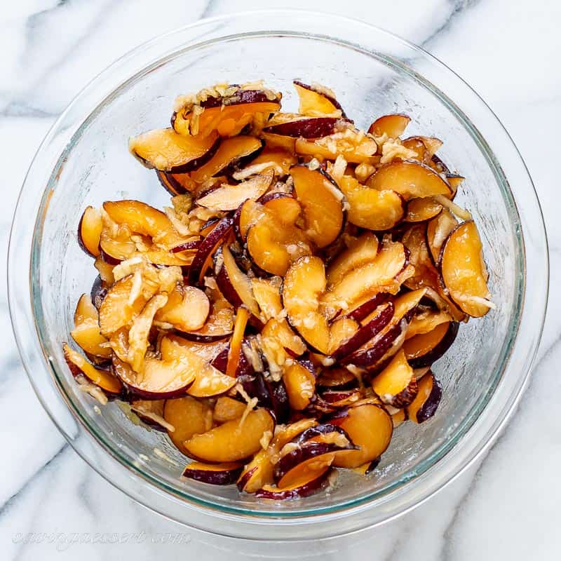 A bowl of sliced plums with sugar and grated apple