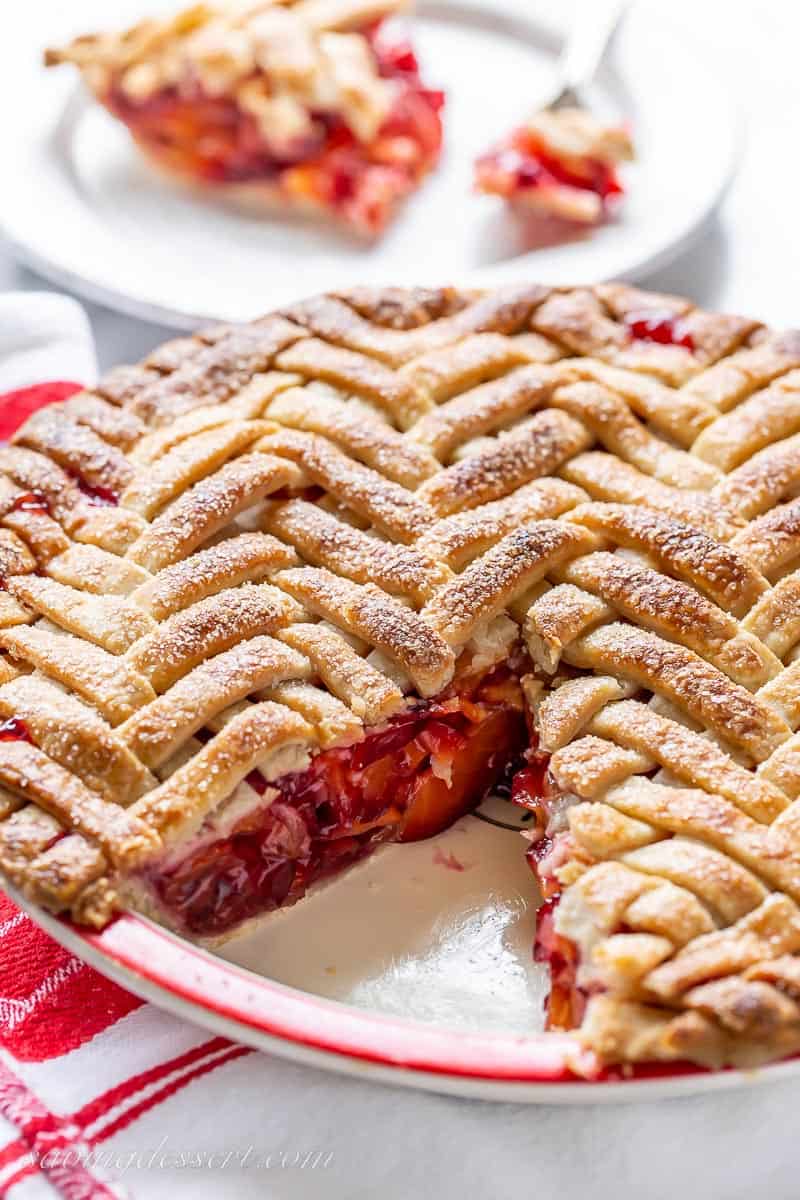 Side view of a sliced plum pie with a herringbone lattice crust