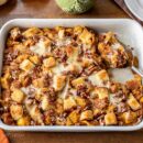 Overhead view of a casserole dish filled with pumpkin bread pudding with pecans on top