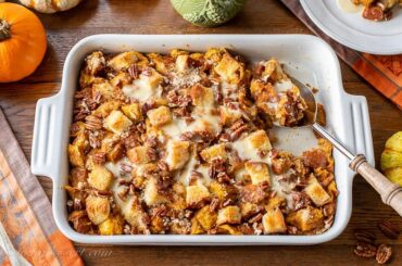 Overhead view of a casserole dish filled with pumpkin bread pudding with pecans on top
