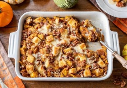 Overhead view of a casserole dish filled with pumpkin bread pudding with pecans on top