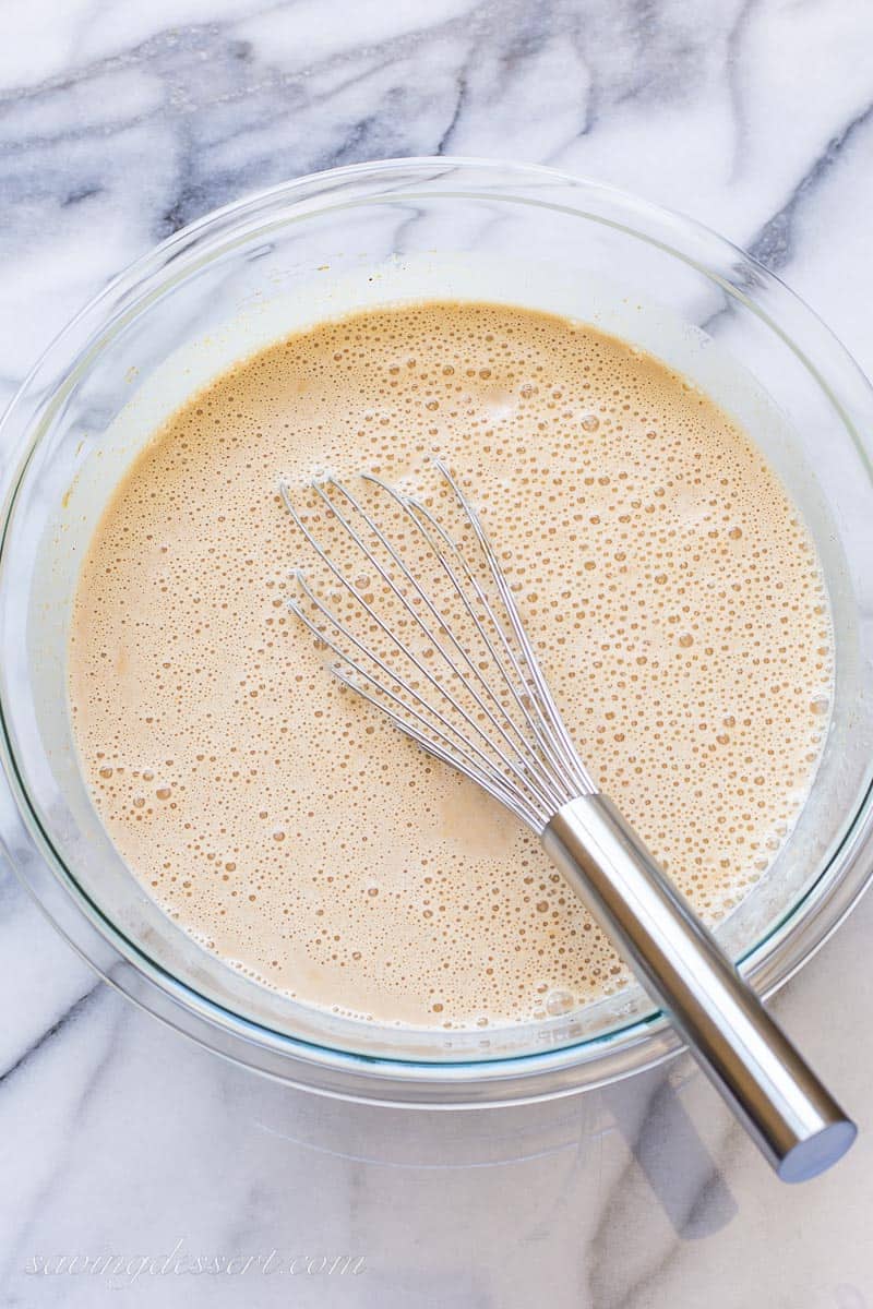 A bowl of pumpkin, sugar, vanilla and half and half with a whisk