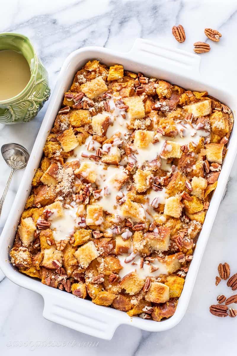 overhead view of a casserole dish filled with pumpkin bread pudding drizzle with bourbon sauce and chopped pecans
