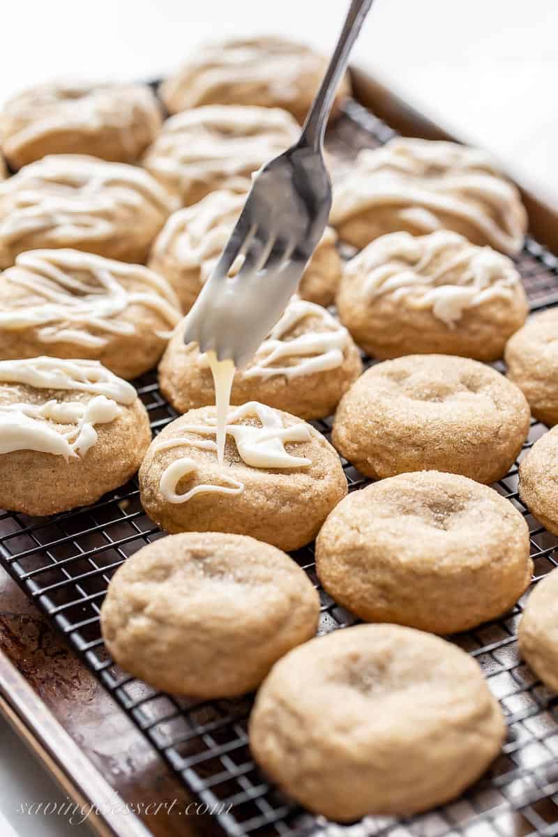 A tray of cookies being drizzled with a white icing