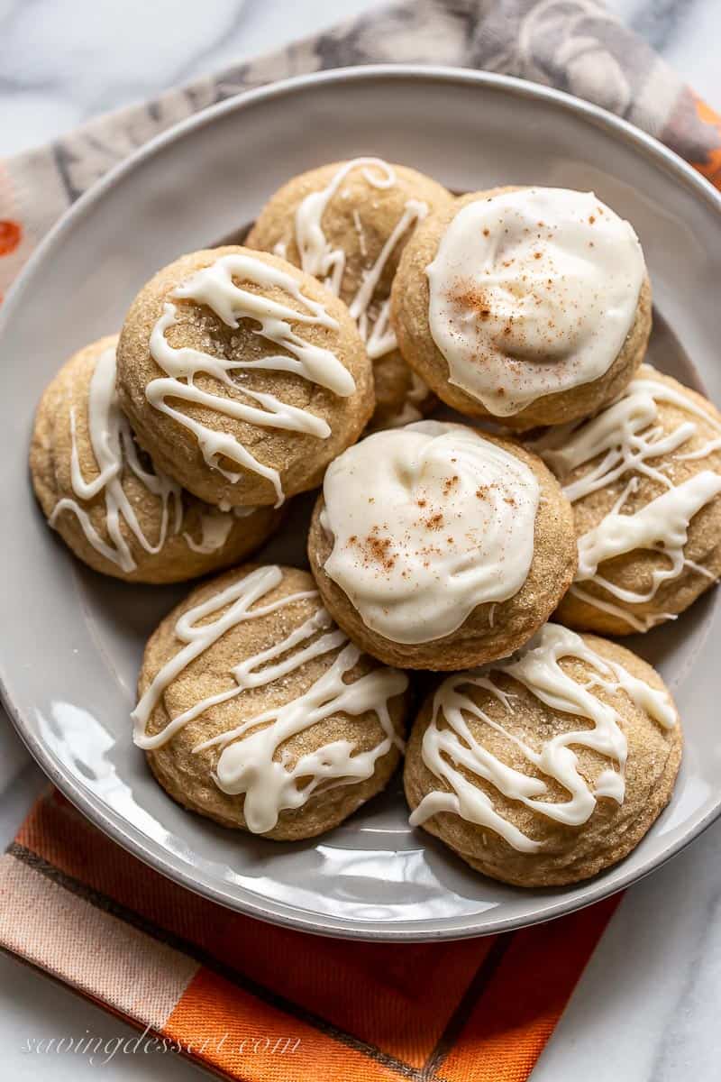 A plate of cookies with some drizzled with iced and a few completely covered in frosting