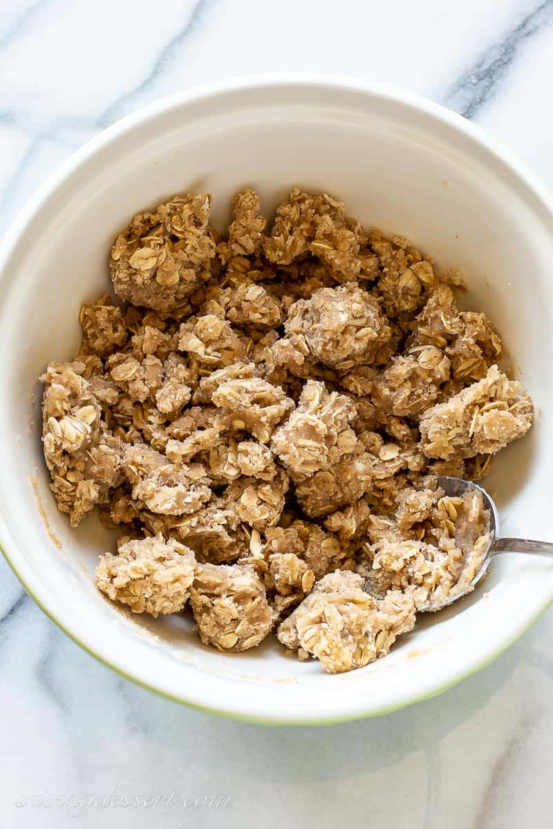 a mixing bowl with an oat crumble topping and a spoon