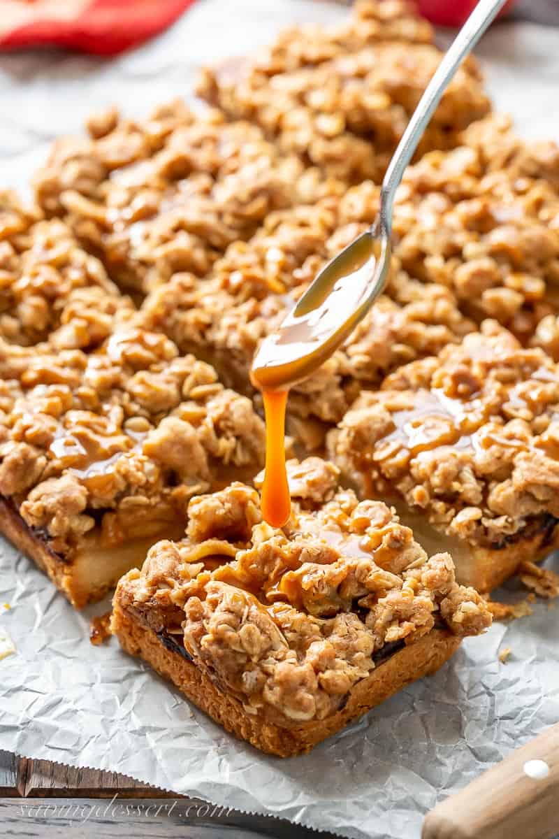 caramel being drizzled over apple bars with a oaty crumble top