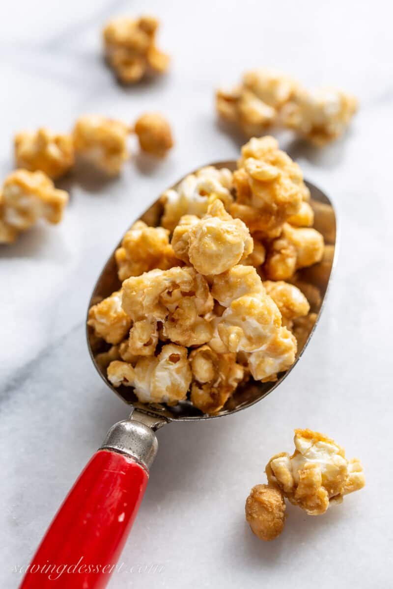 A red scoop filled with caramel popcorn