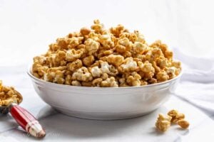 A side view of a big overflowing bowl of caramel popcorn