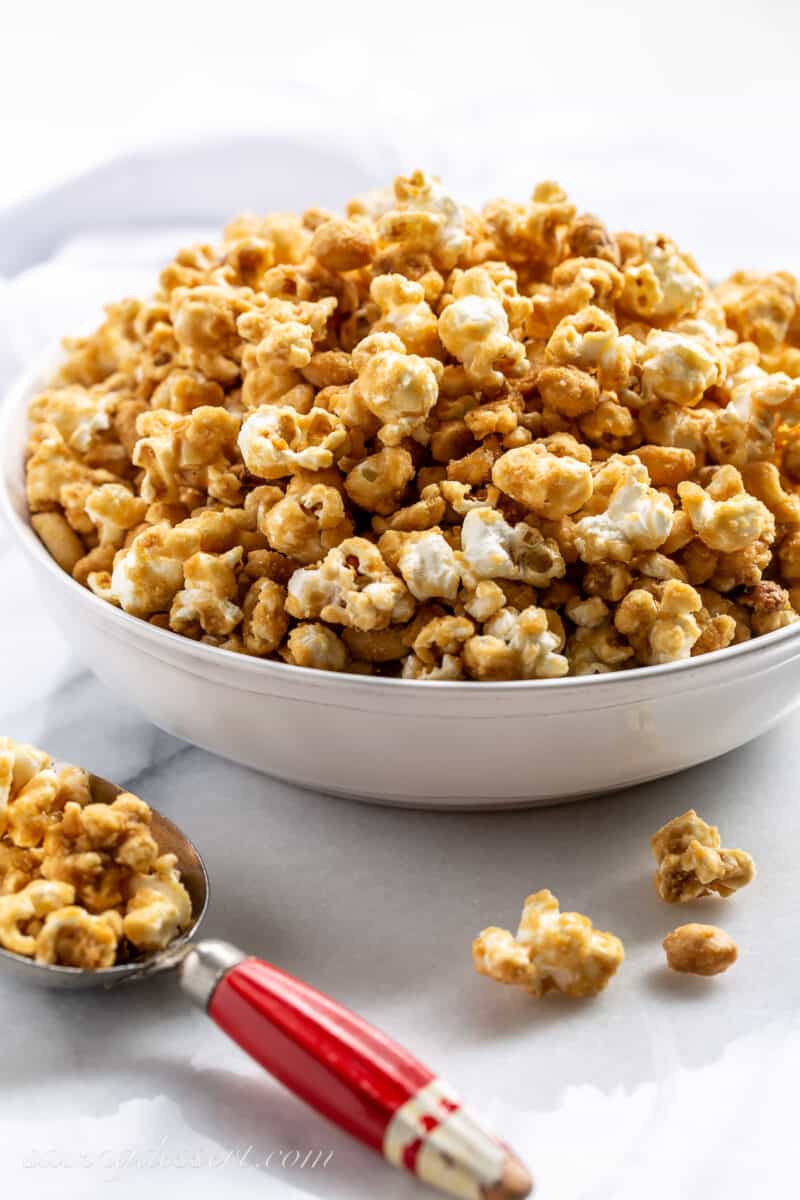 Caramel Popcorn in a large white bowl with a red scoop on the side