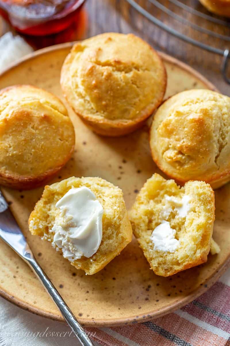 Overhead view of a plate of corm muffins with one split open and topped with butter