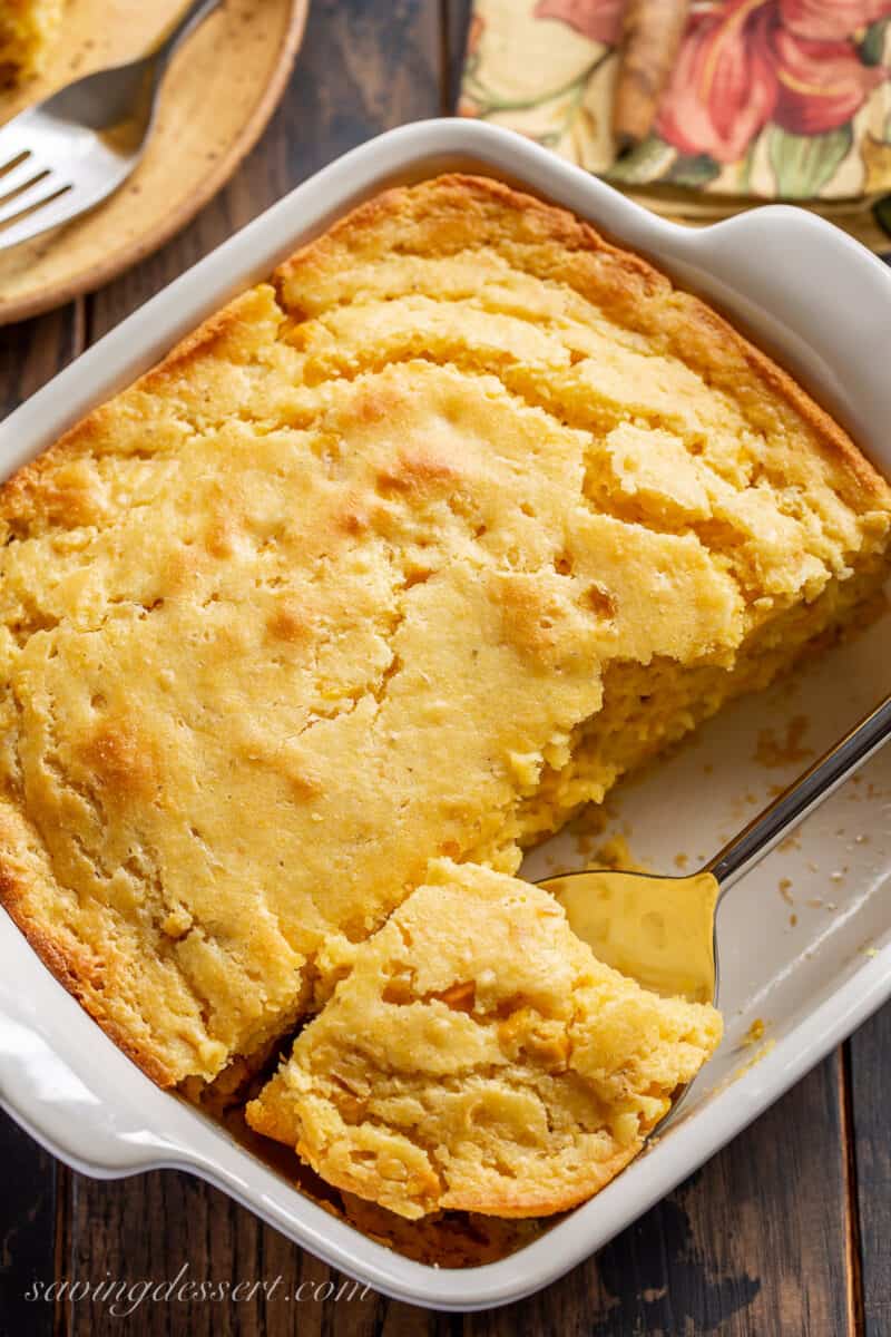 A spoon dish out squares of corn pudding