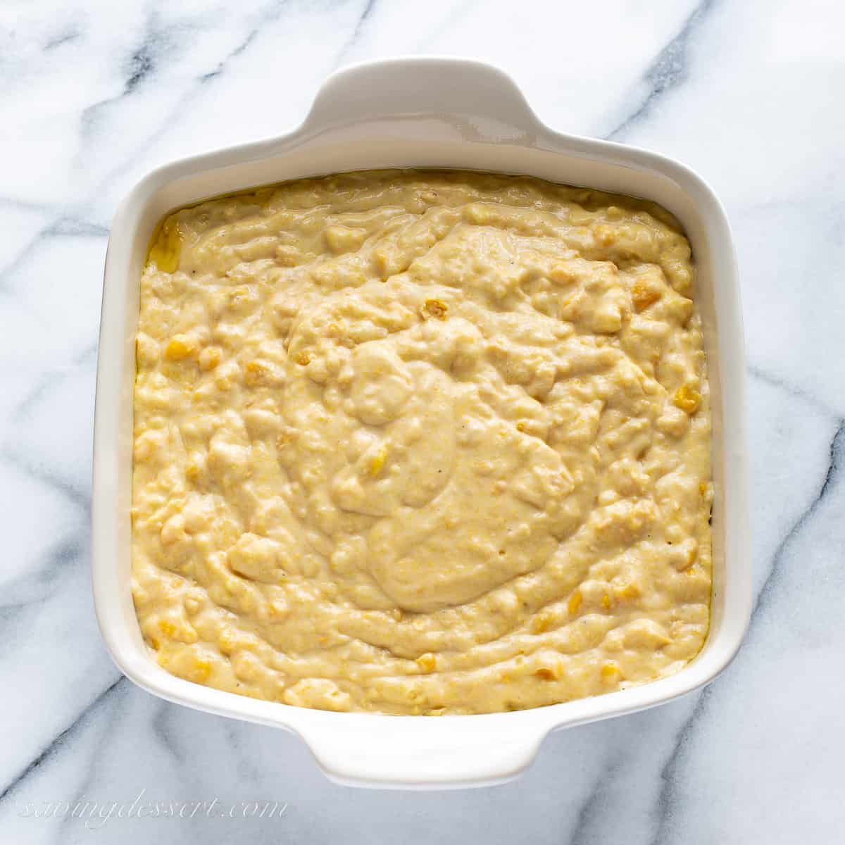 Overhead view of a casserole filled with corn pudding batter ready to bake