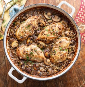 A casserole filled with chicken breasts over a bed of wild rice and mushrooms