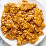 A plate filled with pieces of peanut brittle
