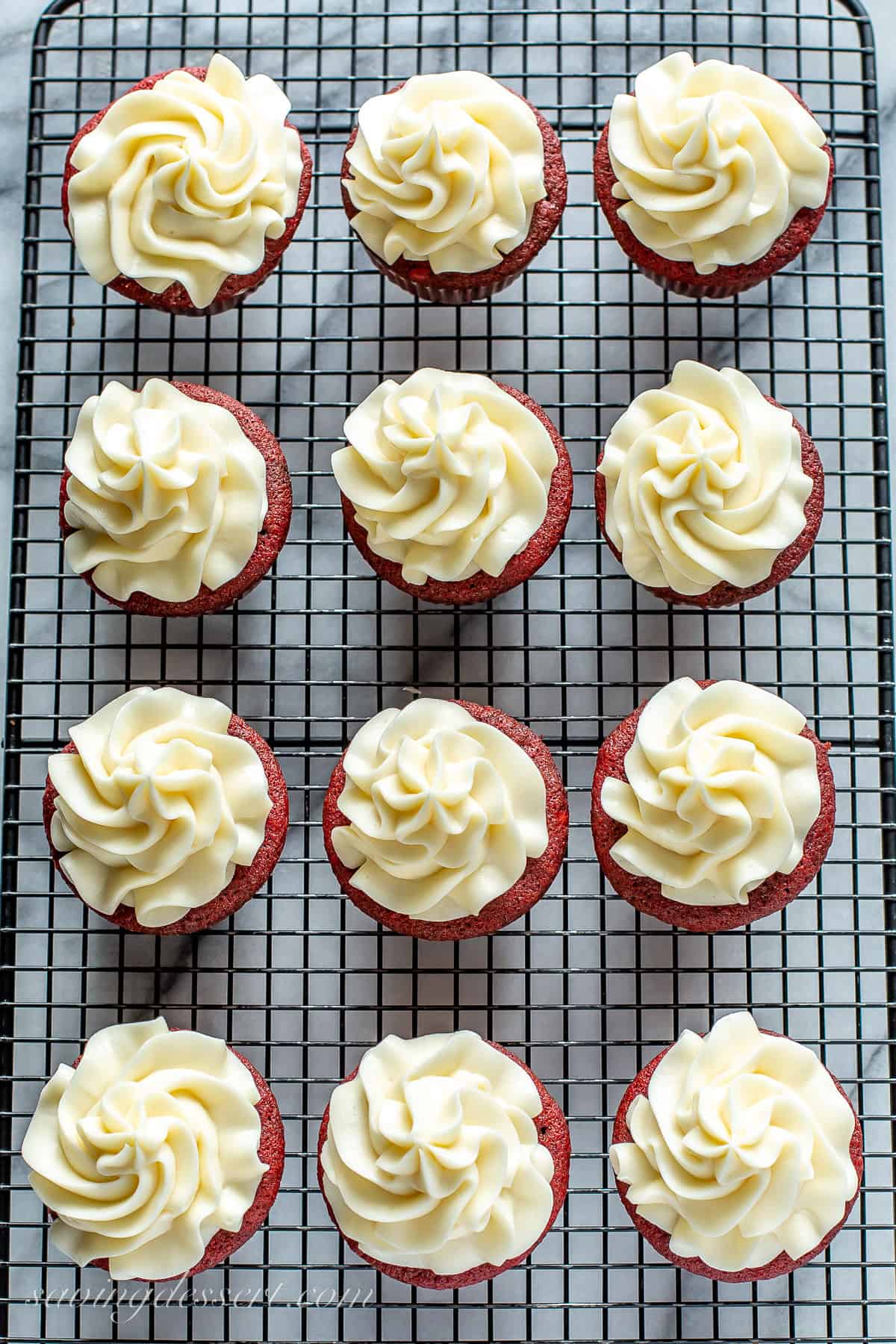 An overhead view of a dozen frosted red velvet cupcakes