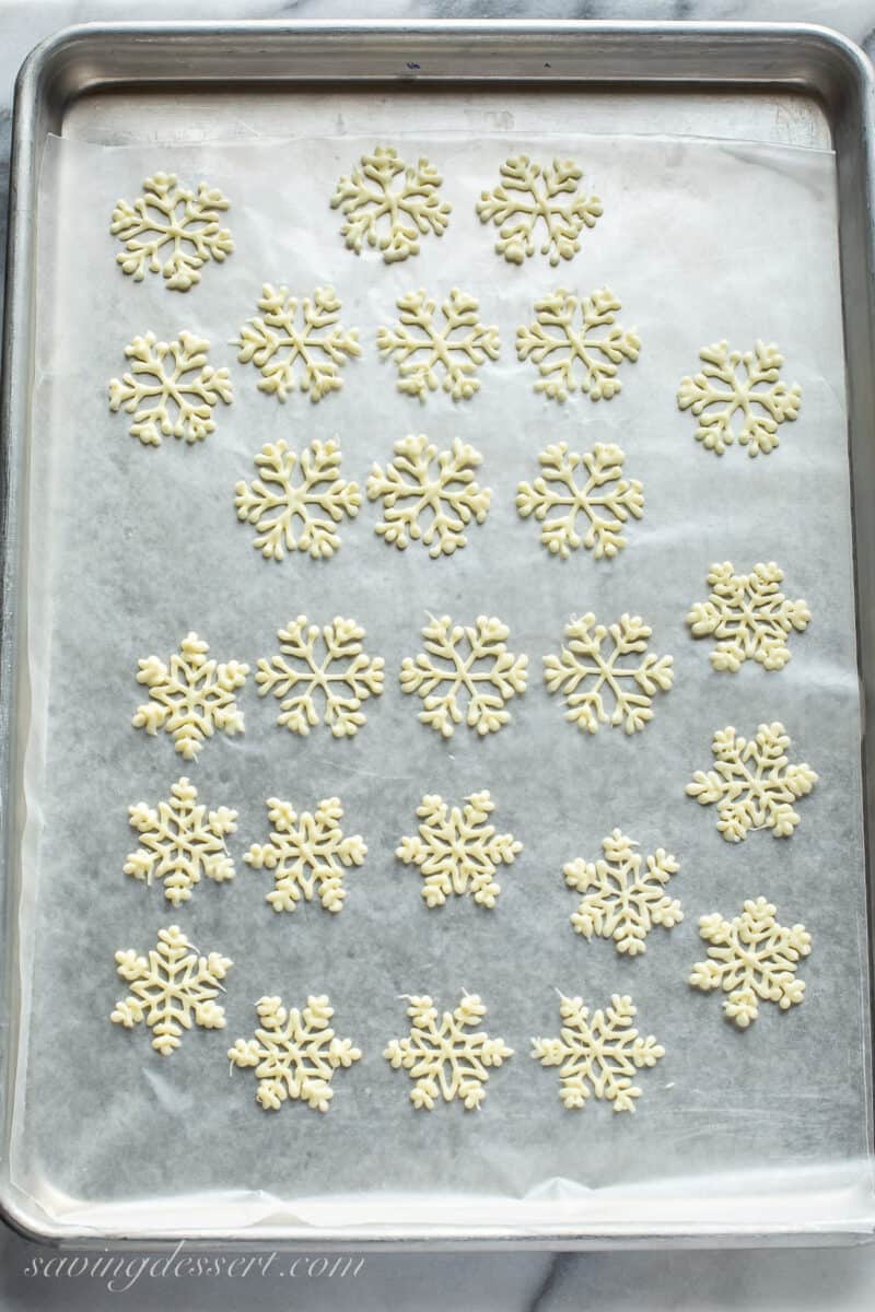 a baking tray filled with white chocolate piped snowflakes