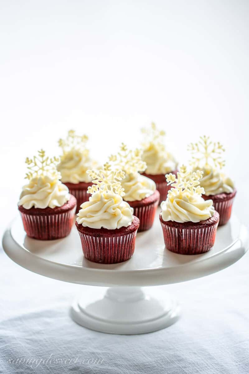 Red velvet cupcakes topped with white chocolate snowflakes on a cake stand