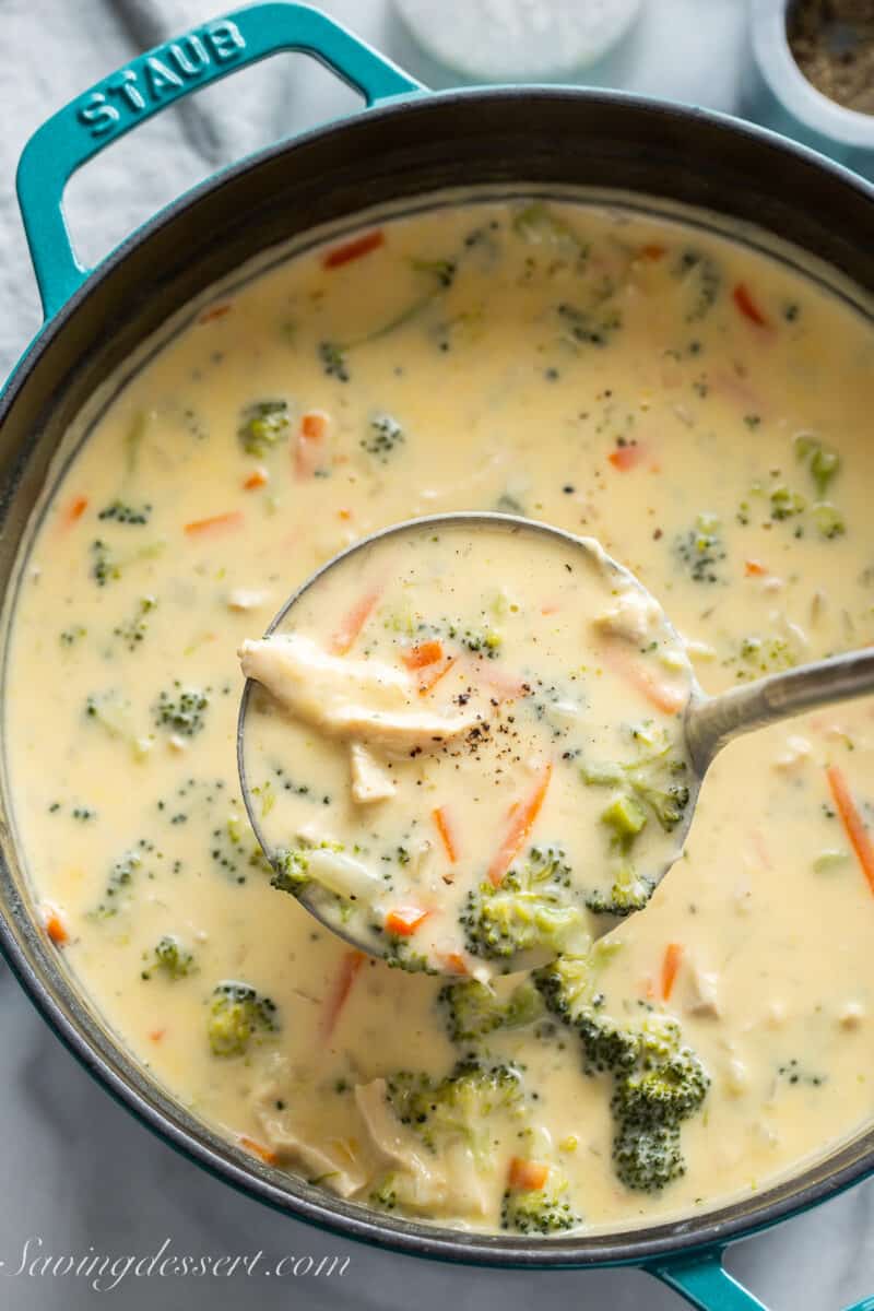cheesy chicken broccoli soup in a pot with a ladle scooping out a serving