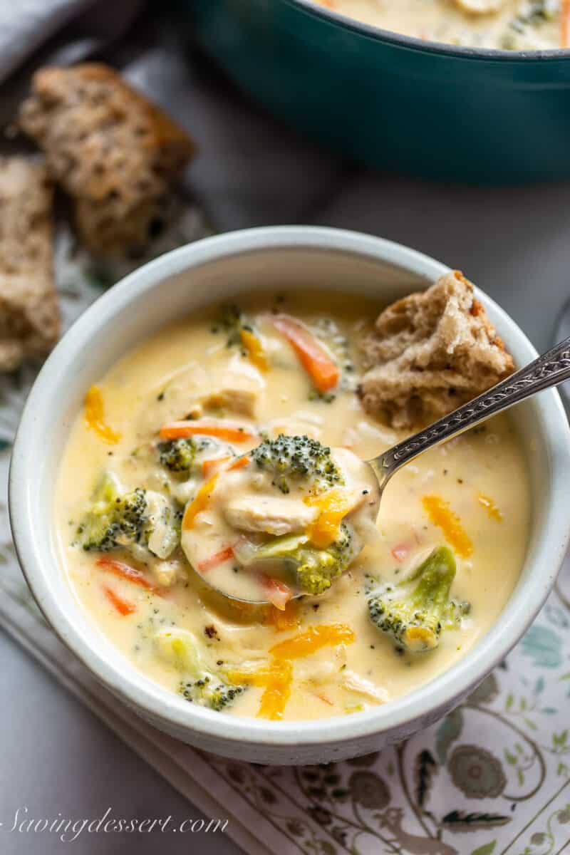 a bowl of cheesy chicken broccoli soup with a spoon scooping out a spoonful