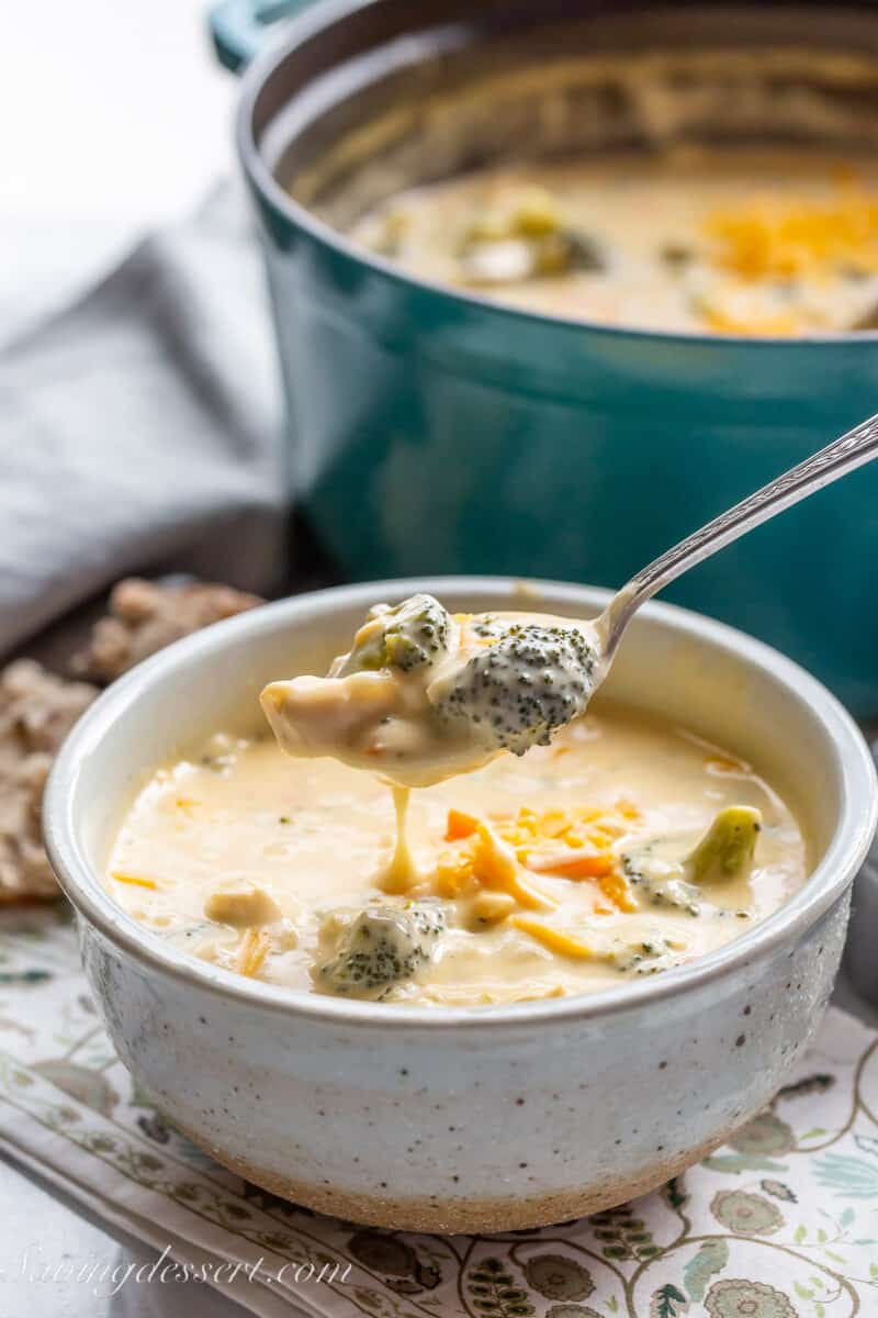 a side view of a bowl of cheesy chicken broccoli soup with a spoonful dipping back into the bowl