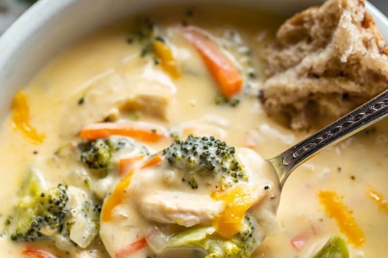 An overhead view of a bowl of chicken broccoli soup with cheese.