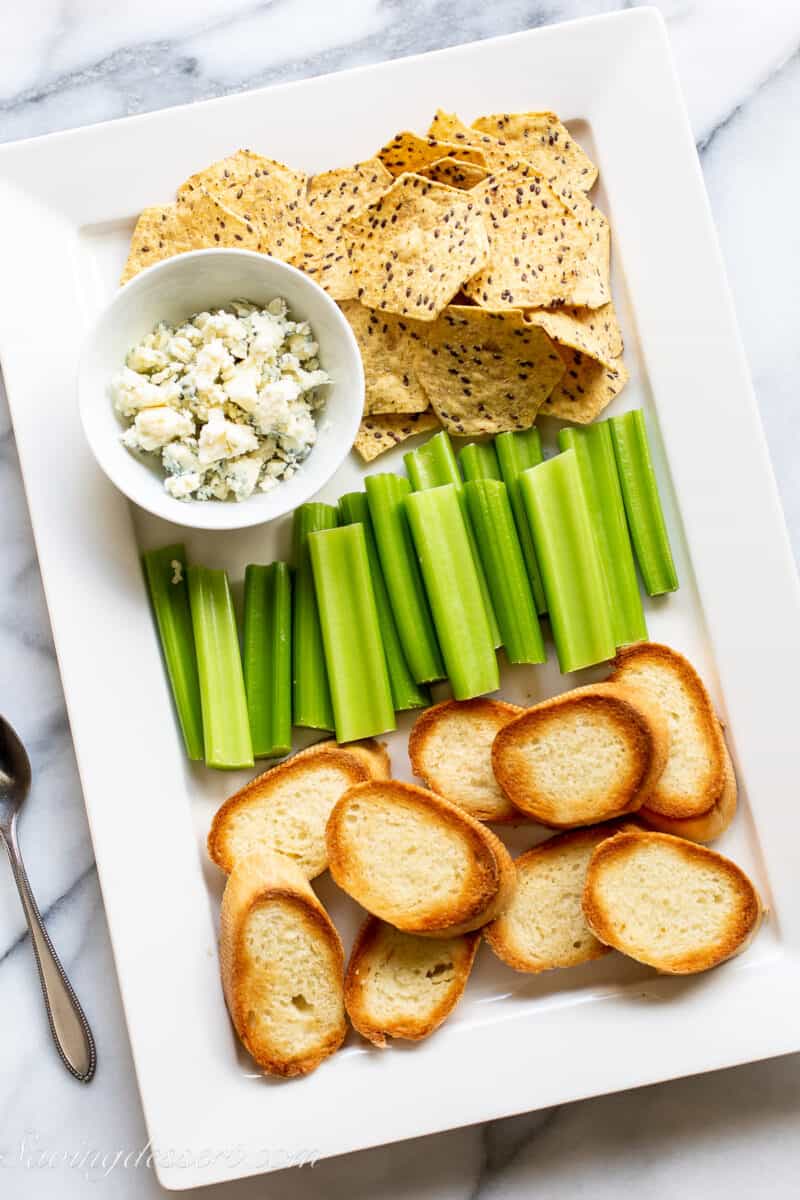 a platter filled with baguette slices celery blue cheese and chips