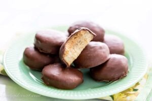 A plate of homemade Tagalong cookies showing one halved with a peanut butter filling on top of a shortbread cookie