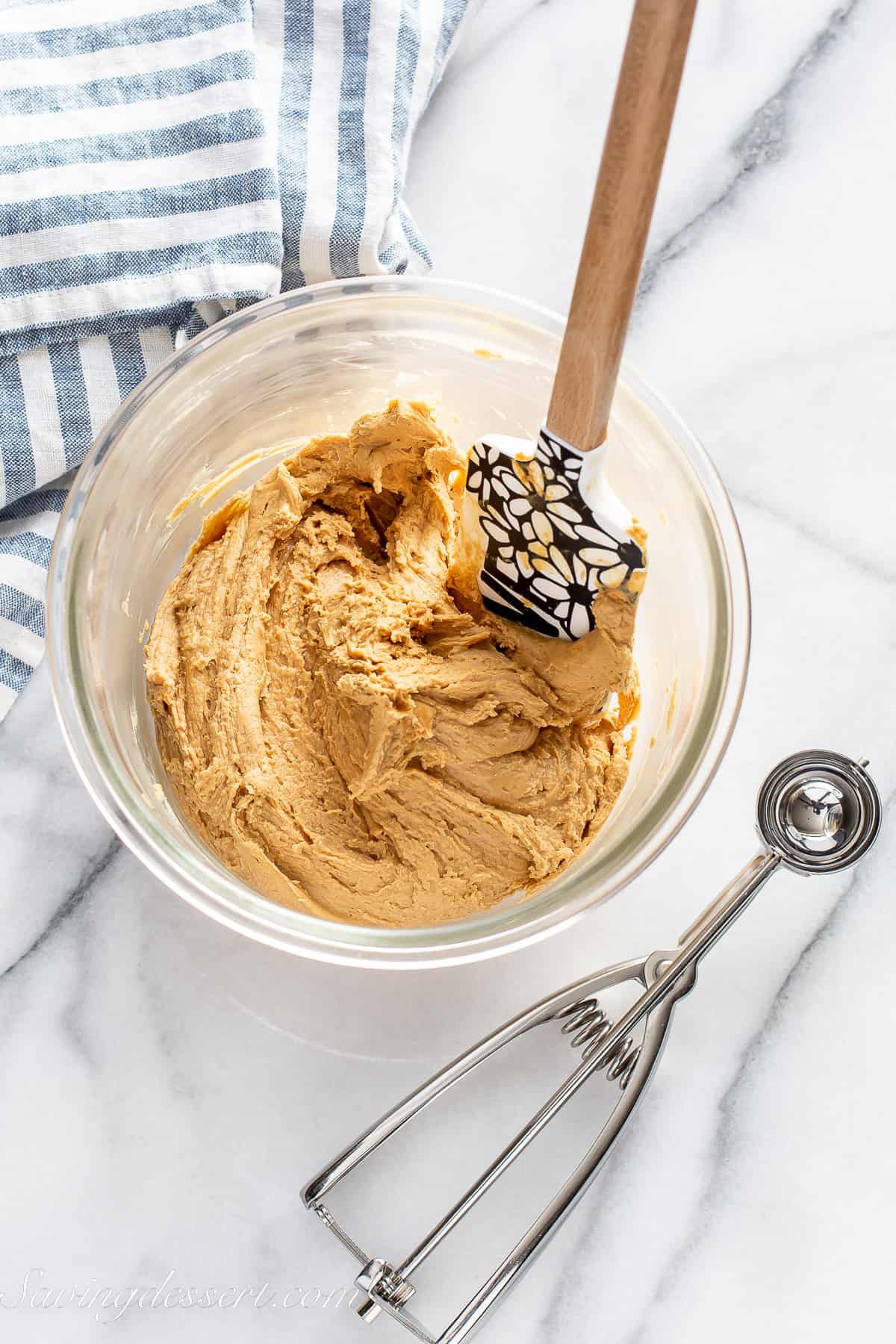a bowl of a peanut butter mixture with a cookie scoop on the side