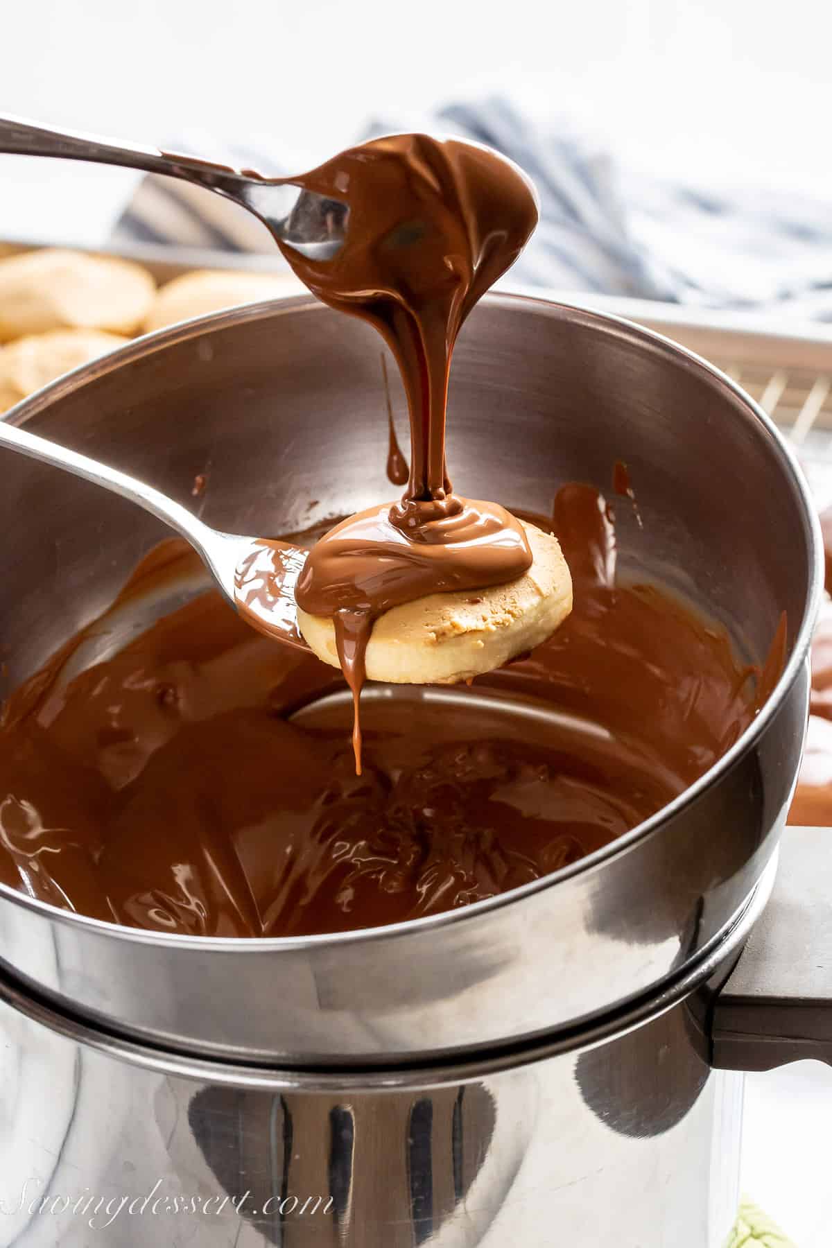 a shortbread cookie topped with peanut butter being drizzled with chocolate