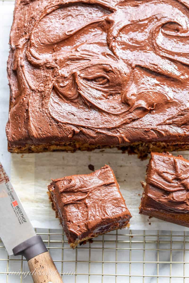 an overhead view of a single layer banana cake sliced into squares and topped with chocolate frosting