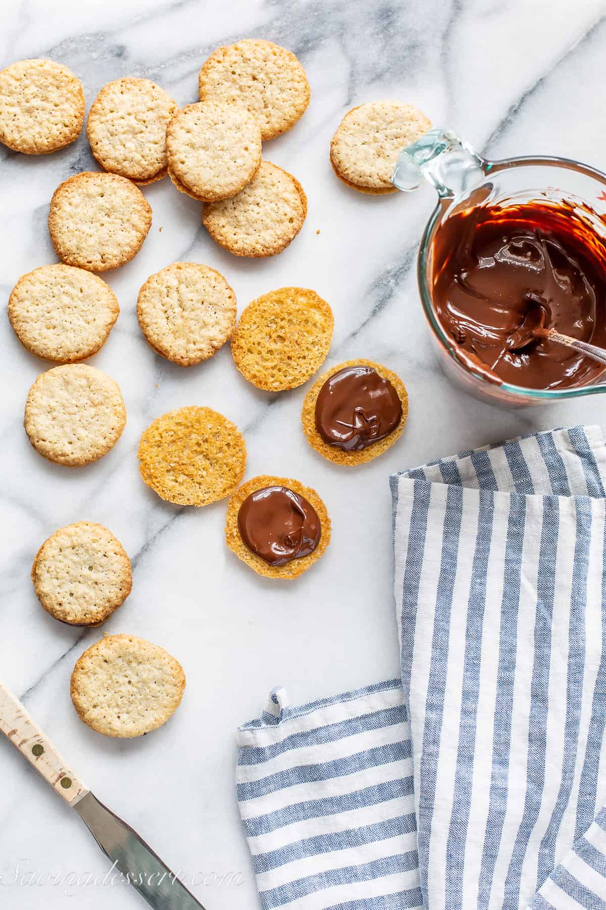 Overhead view of small Brussels cookies being filled with melted chocolate