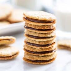 A stack of Brussels cookies with a glass of milk nearby