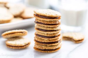 A stack of Brussels cookies with a glass of milk nearby